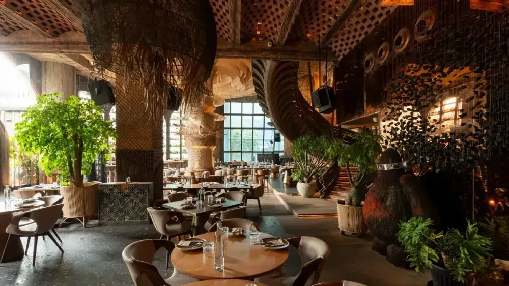 Comedor elegante con plantas, decoración tejida y mesas iluminadas de Noches De Colombia